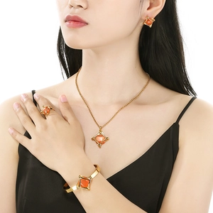 Close-up of geometric jewelry set with orange stones and gold finish on model