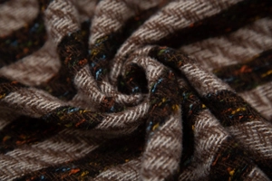 Close-up of herringbone weave wool scarf with brown tones and colorful speckled yarn details