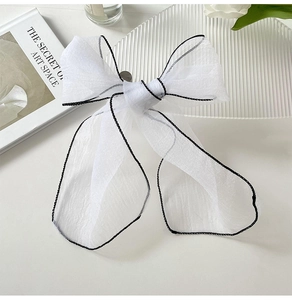 Close-up of white organza ribbon with black edge detailing and elegant bow styling