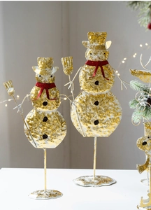 Close-up of golden hammered metal snowmen with red scarves for Christmas tabletop decor