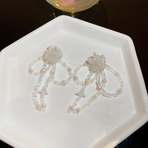 Details von weißen Blumenohrringen mit Perlenquasten auf einem Keramikteller