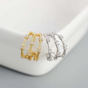 Macro detail of triple-layer bamboo earrings with micro-set diamonds in gold and silver