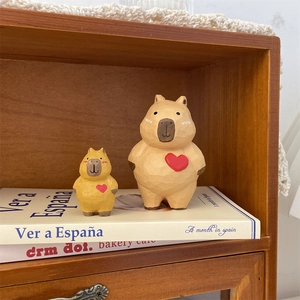 Détail de deux figurines capybara en bois sculpté main avec cœurs rouges sur étagère