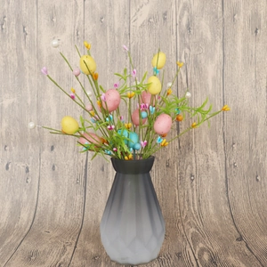 Dettaglio di rami con uova di Pasqua colorate in un moderno vaso grigio satinato