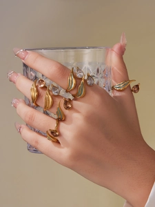 Detailed view of hand wearing gold waterdrop zircon rings with green enamel accents