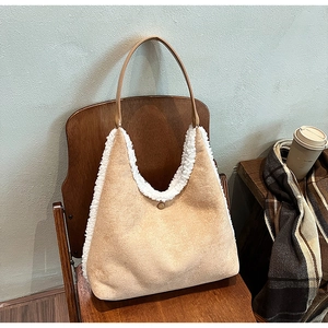 Close-up of beige suede tote bag with white plush trim and brown strap on a chair