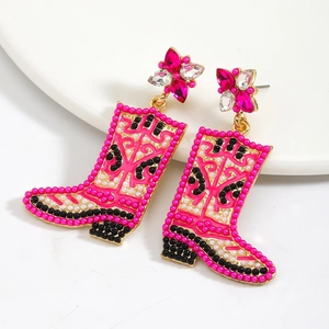 Detailed view of pink cowboy boot earrings with colorful beads and rhinestones on a white plate