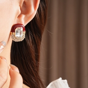Close-up of vintage red enamel earrings with crystal centerpiece and diamond-like trim