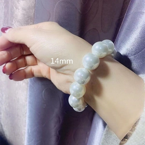Close-up of a 14mm large round white pearl elastic bracelet worn on a female wrist
