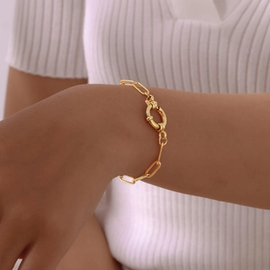 Detail of gold rectangular link chain bracelet with a large spring ring clasp on wrist
