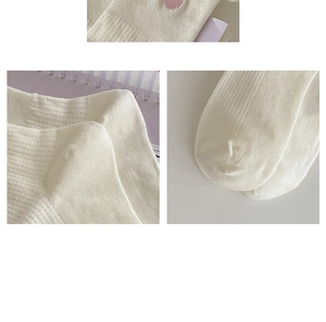 Detail view of white ruffled socks showing heart embroidery and ribbed knit texture