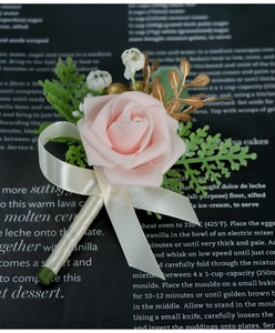 Detail of pink PE rose boutonniere with green leaves and cream ribbon bow tie
