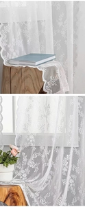 Detail of white lace curtains on a wooden stool and hanging by a window with soft light