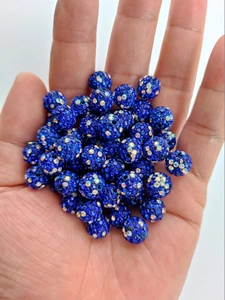 Close-up of a 10mm dark blue clay bead with iridescent rhinestones held by hand