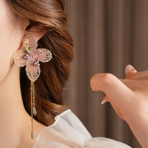 Detailed shot of vintage gold knit flower earrings with green gemstone and tassel