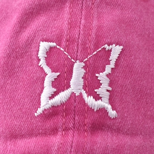 Pink washed cotton baseball cap featuring a detailed white butterfly embroidery on the front