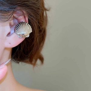 Macro shot of silver shell ear cuff with vertical ridges on model ear