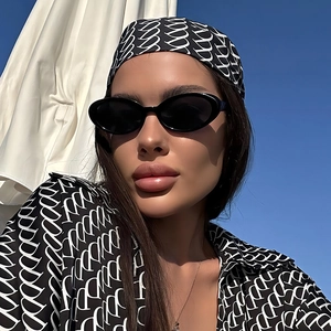 Close-up of vintage oval sunglasses paired with a designer-style printed headscarf