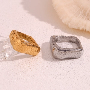 Détail de bagues géométriques carrées en or et argent avec gouttes d'eau sur la surface