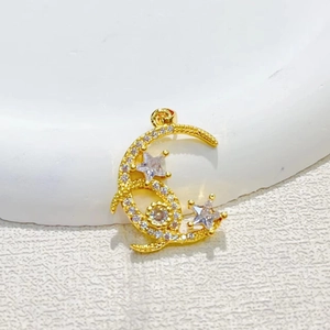 Gold moon and star pendant with sparkling cubic zirconia on a white textured background
