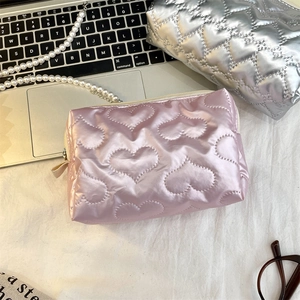 Detailed view of pink and silver heart-quilted makeup bags with zipper closure