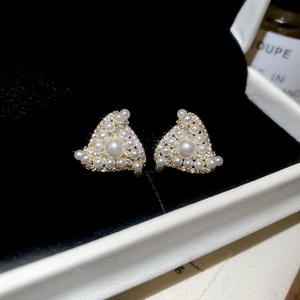 Macro shot of triangle pearl earrings with gold plating and sparkling zircons in a box