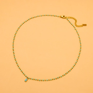 Detail of beaded necklace with gold chain and green rectangular pendant on orange background