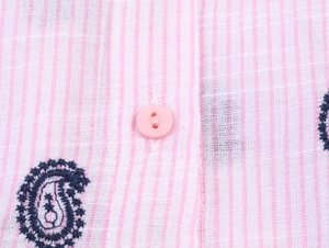 Détail macro du tissu à rayures roses avec broderie cachemire et bouton assorti du haut