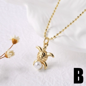 Dettaglio della collana con pendente a tartaruga dorata e perla su sfondo in ceramica