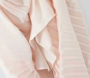Close-up of elegant pleated light pink chiffon fabric showing soft drape and texture