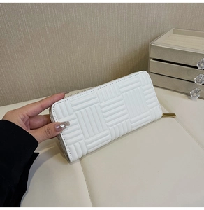 Detail of white long zip wallet featuring woven texture and gold zipper hardware