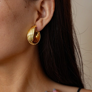 Close-up of gold layered twisted hoop ear cuff worn on model for elegant style