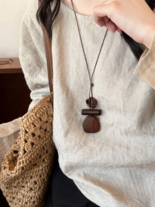 Detail of bohemian wood and resin geometric pendant on a brown long cord necklace