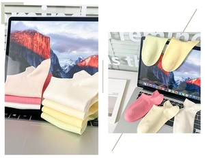 Close-up of pastel cotton boat socks in pink and yellow on a clean desk workspace