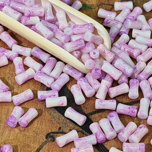 Détail macro de perles en forme de bambou marbré violet pour la création de bijoux