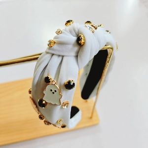 Détail d'un serre-tête d'Halloween blanc avec strass et breloque fantôme sur support doré