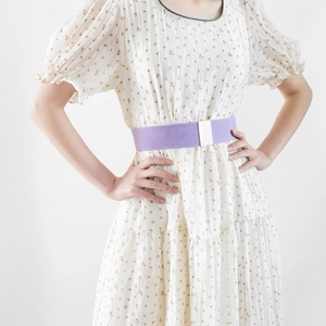Detail shot of a purple elastic cinch belt with silver buckle on floral dress