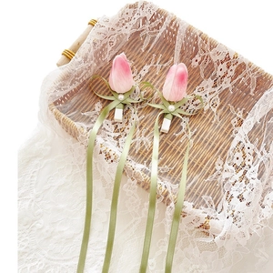 Pink tulip hair clips with green silk ribbons and pearls on white lace basket decoration