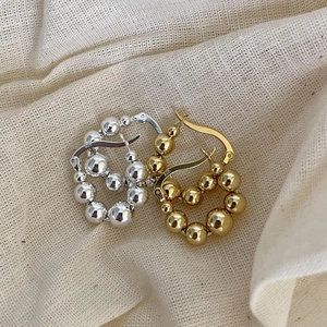 Detail of S925 sterling silver beaded hoop earrings in gold and silver finishes