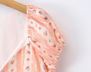 Dettaglio ravvicinato della stampa rosa rosa su maniche a sbuffo con pizzo bianco fine