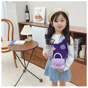 Detail of girls purple quilted silicone handbag with decorative pearl handle and cute charms