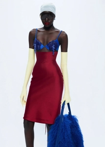Détail de jupe en satin rouge avec haut floral bleu et longs gants d'opéra jaunes