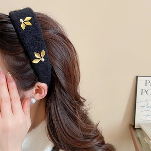 Detail of vintage black flocked headband with gold leaves and white pearls on a model