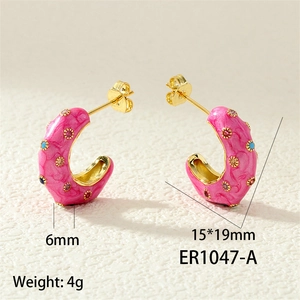 Macro detail of gold plated pink enamel C-hoop earrings with colorful zircon stones