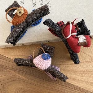 Detail of three vintage knit bow hair claws with floral baskets and red horse designs