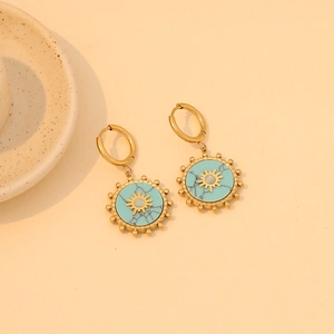 Golden turquoise sun pattern earrings set on a minimalist beige ceramic plate display