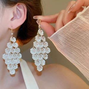 Detail of elegant cream shell tassel earrings with zircon studs and gold finish