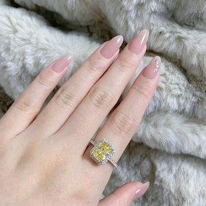 Radiant cut yellow gemstone ring with pavé diamond halo on model fingers