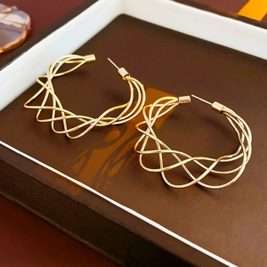 Detailed view of intertwined hollow C-shape earrings with twisted metallic gold finish