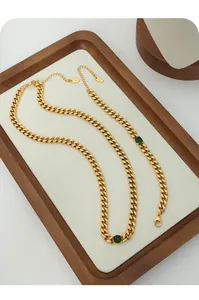 Detail of gold Cuban chain necklace with green stones and K18 hallmark stamp on jewelry set